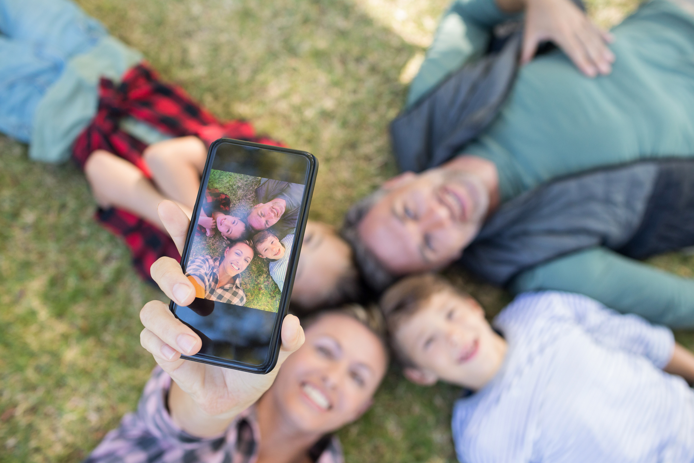 Happy family lying on the grass and taking selfie